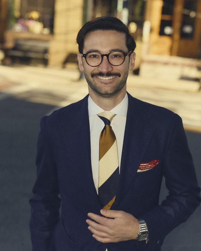 Portrait of Rob Craven in a navy suit, smiling, in Wickford village